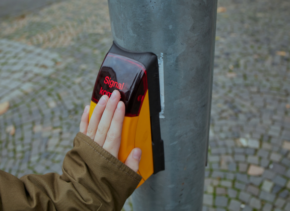 Eine Hand berührt den Sensor eines Ampeltasters