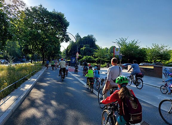 Bicibus Hamburg Eine Gruppe von Kindern fährt auf ihren Rädern auf der Straße. Sie werden von Erwachsenen begleitet.