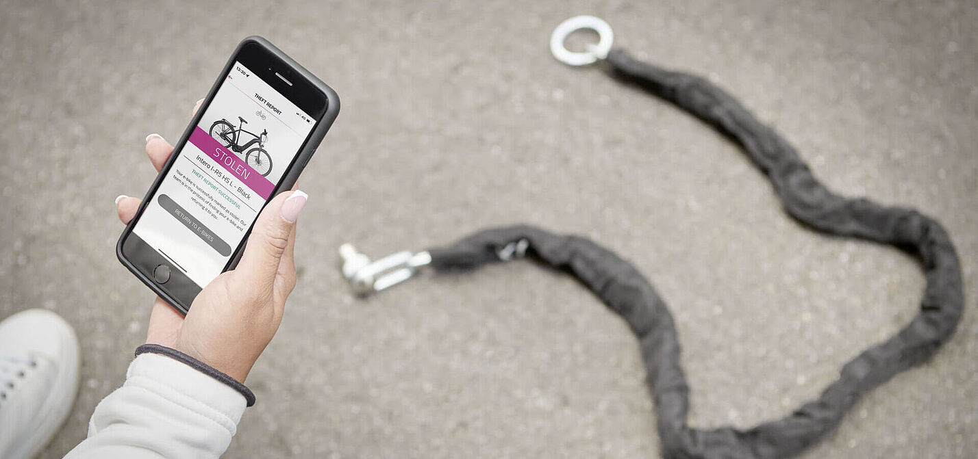 Person zeigt Smartphone mit "Gestohlen"-Anzeige vor offenem Fahrradschloss. Person zeigt Smartphone mit "Gestohlen"-Anzeige vor offenem Fahrradschloss.